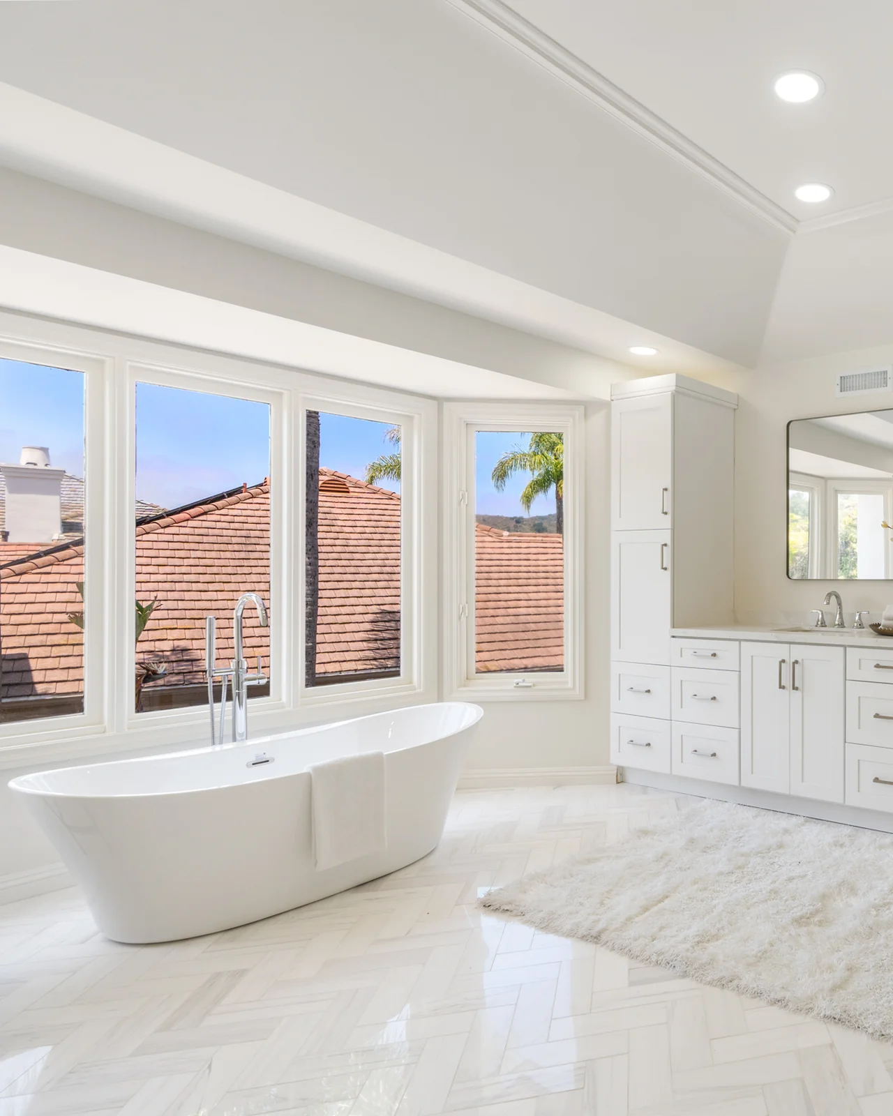 Primary bathroom remodel coordinated by Coto Bath Co. — freestanding tub, bay window with Coto de Caza views, and herringbone marble floor