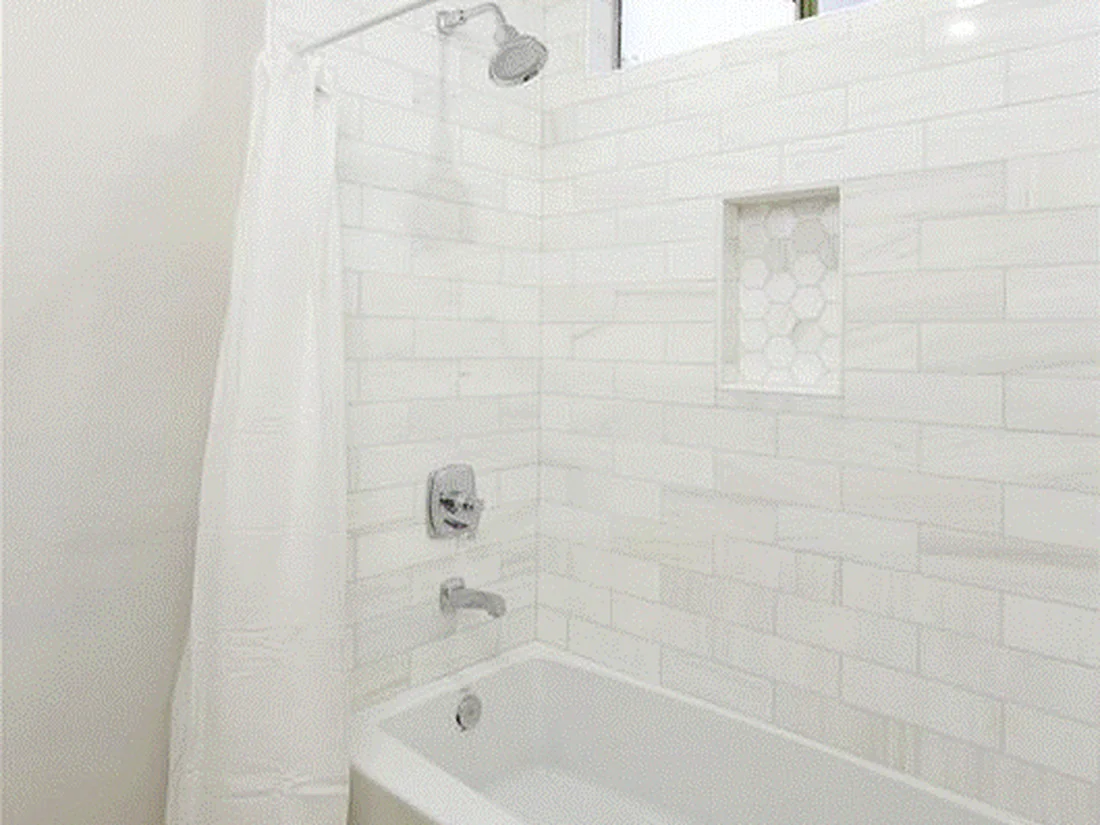 Mission Viejo hall bathroom remodel with white subway tile, marble hex niche, and warm wood-look floors