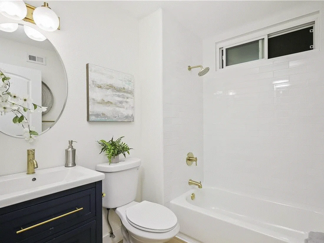 Mission Viejo bathroom remodel with navy vanity, brass fixtures, and white subway tile tub surround
