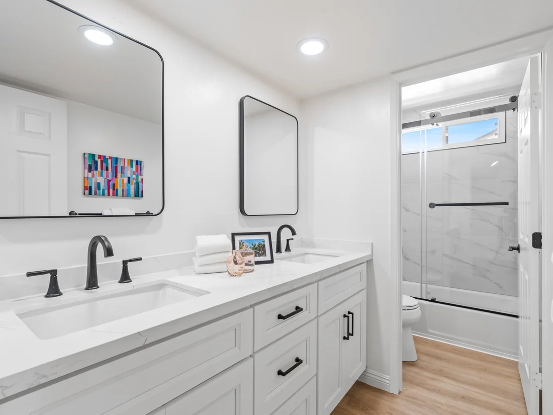 Modern hall bath remodel in Mission Viejo with double vanity, calacatta marble counters, and matte black fixtures