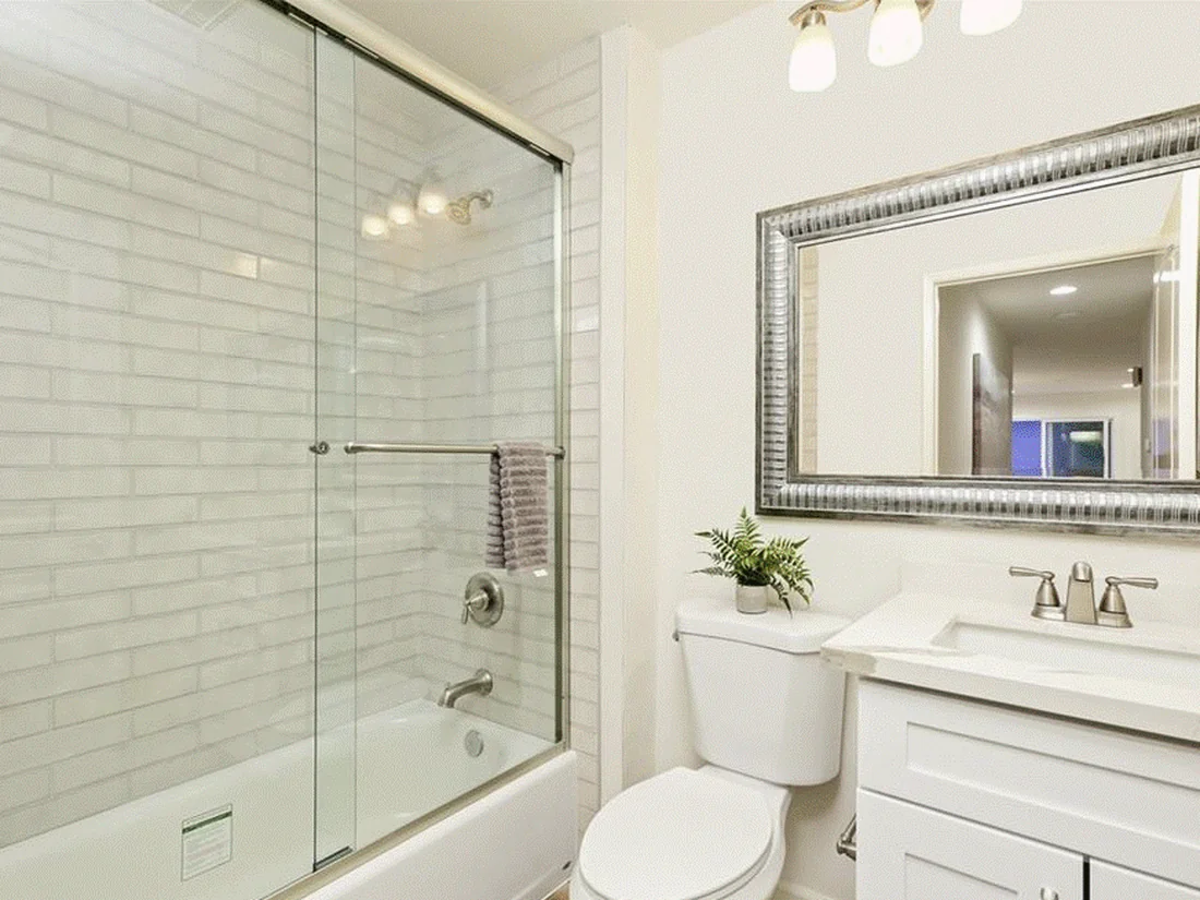 Mission Viejo bathroom remodel with sliding glass tub-shower, elongated subway tile, and framed silver mirror
